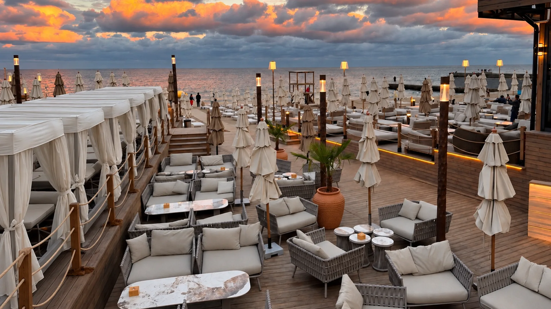 Seaside resort terrace furnished with lounge seating and umbrellas at sunset